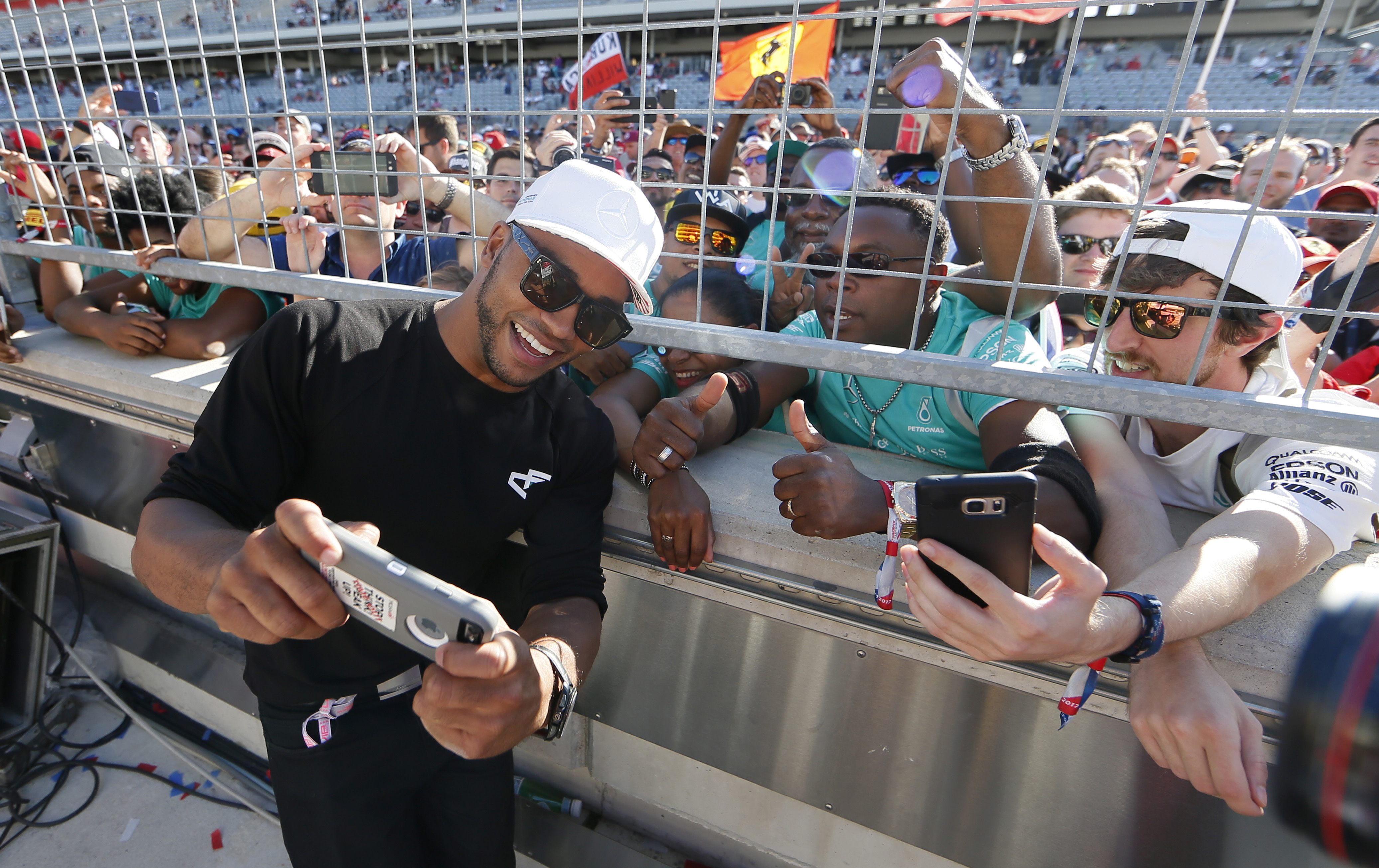 Nicolas Hamilton, left, brother of Mercedes driver Lewis Hamilton, takes a photo with fans following the Formula One U.S. Grand Prix auto race at the Circuit of the Americas- AP